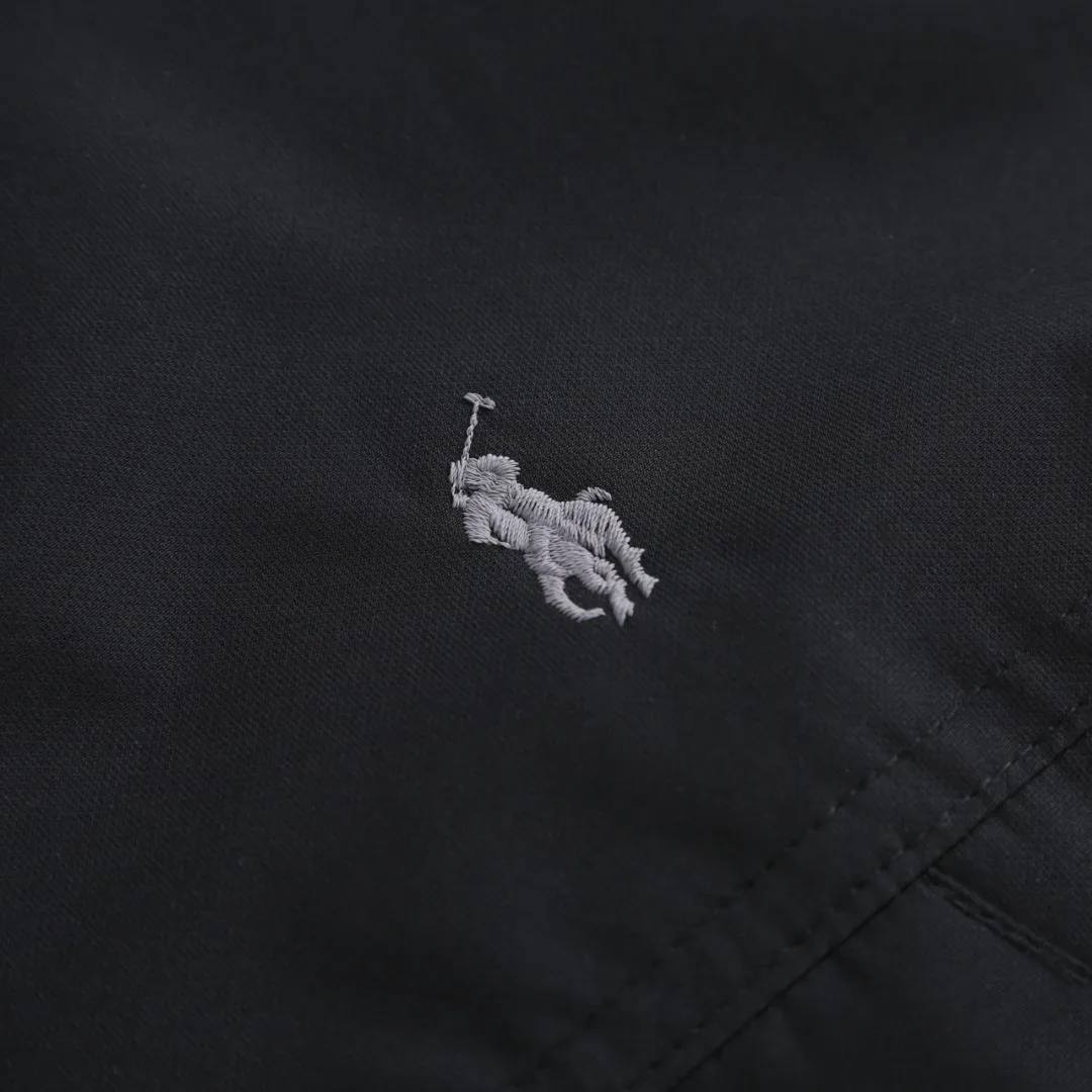 P970 Ralph Lauren Logo Hooded Down Jacket Fabric selection: High-density nylon taffeta with a density of about 210T-300T, smooth and slightly matte surface, excellent windproof and waterproof performance (with DWR water-repellent treatment), strong wrinkle resistance and easy care, in line with the "durable and practical" positioning of American leisure.  Lining fabric: 100% polyamide is used to create the lining. The high-density and tight weaving process prevents fine lint from emerging from the gaps in the fabric. The smooth surface improves the putting on and taking off experience, and the excellent wear and tear resistance ensures damage caused by frequent use, while the light and soft texture does not affect the overall weight.  High-quality filling: 90 white duck down is selected, with a weight of 220g, ensuring excellent thermal insulation performance. After strict screening and processing, the velvet is not easy to drill, ensuring durability. Style and cutting process: The classic jacket has a slightly loose fit, with a slightly dropped shoulder line (the shoulder width is 1-2cm wider than the standard fit). The length reaches the hips, and the sleeves are slightly tapered straight sleeves, taking into account freedom of movement and casual style.  Details: The adjustable Velcro on the cuffs allows you to freely adjust the tightness according to the thickness of your wrist and personal preferences, effectively preventing cold wind from intruding, and improving warmth retention performance.  In terms of storage, the two front zipper pockets are convenient for you to place frequently used items, and the zipper design ensures that items are not easily lost. A built-in pocket on the left side of the chest provides a safe storage space for some small private items.  The drawstring design at the hem allows you to adjust the shape of the jacket according to your body shape and dressing needs. Whether it is loose and casual or slim and neat, you can easily control it.  Embroidery technology: Polo horse logo on the left chest: flat satin stitch embroidery (satin embroidery), embroidery thread: 100% polyester high color fastness embroidery thread (the color number is consistent with the brand’s standard red color card), stitch density 12-15 stitches/cm, the outline of the horse logo is clear, and the details of the rider and horse are burr-free.  Embroidery positioning: precise positioning through the template (12cm from the neckline and 8cm from the placket) to ensure left and right symmetry and centering.  Accessories: One-to-one customized zipper sling, one-to-one customized zipper puller, one-to-one customized washable label SIZE: S M L XL
